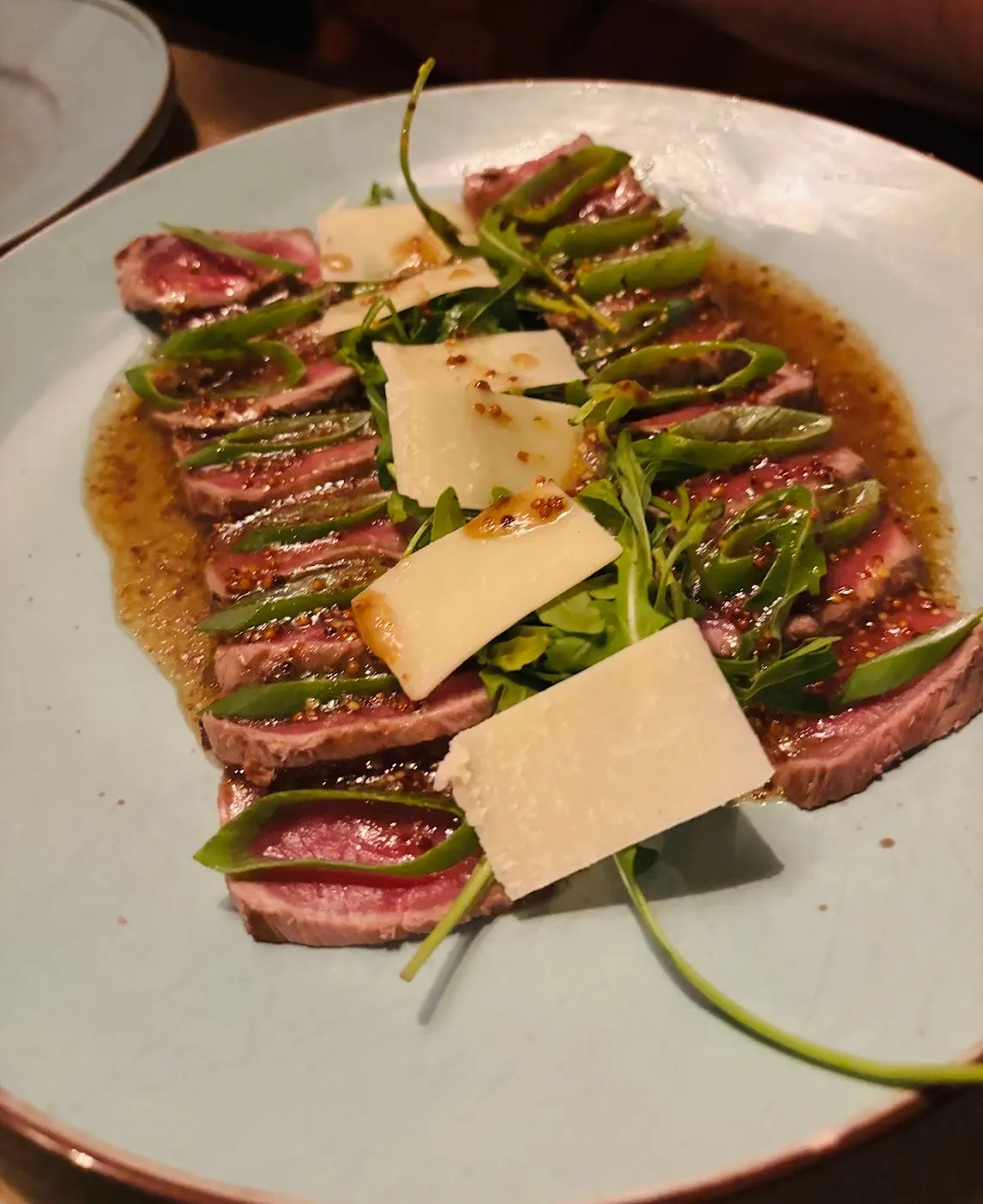 Láminas de carne a la plancha con rúcula y lascas de queso